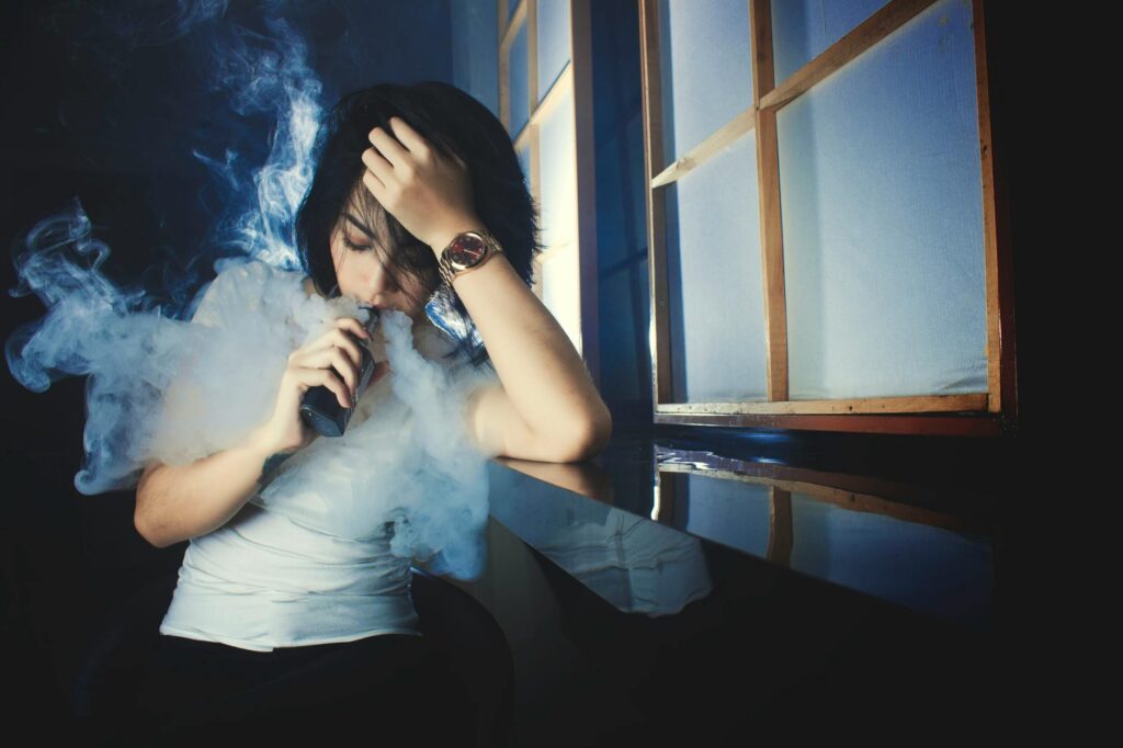 young woman smoking e cigarette in darkness